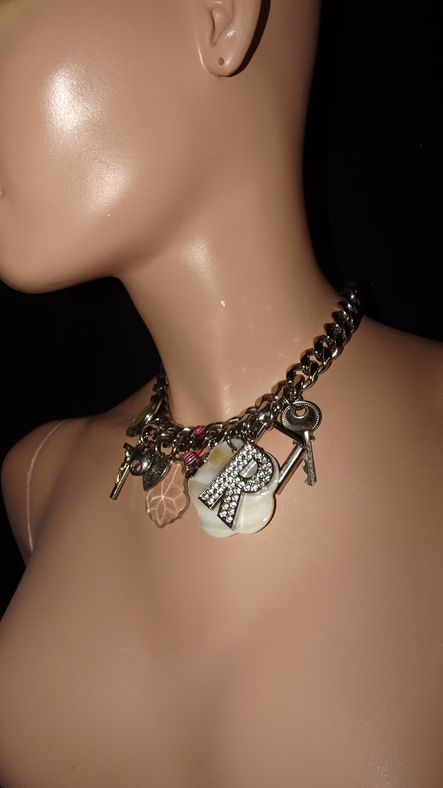 Upcycled charm necklace by weARCHIVE with thick stainless steel chain, featuring vintage charms: key, rhinestone R, cross, shell and more