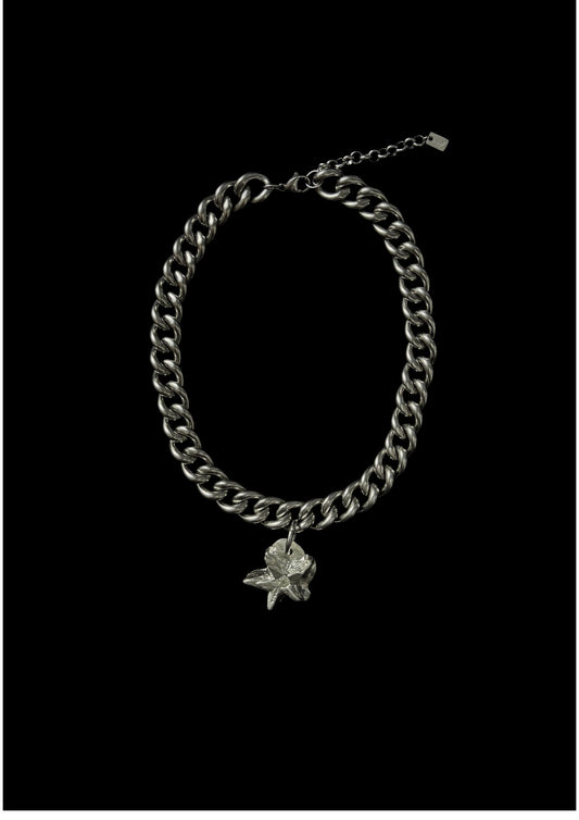 Silver chain bracelet with a flower charm on a black background