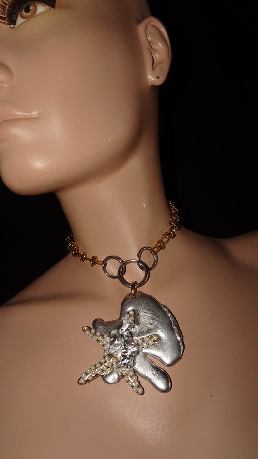 Statement choker by weARCHIVE with sculpted stainless steel pendant featuring a pearl-beaded starfish on organic form, paired with gold wire chain and rings.