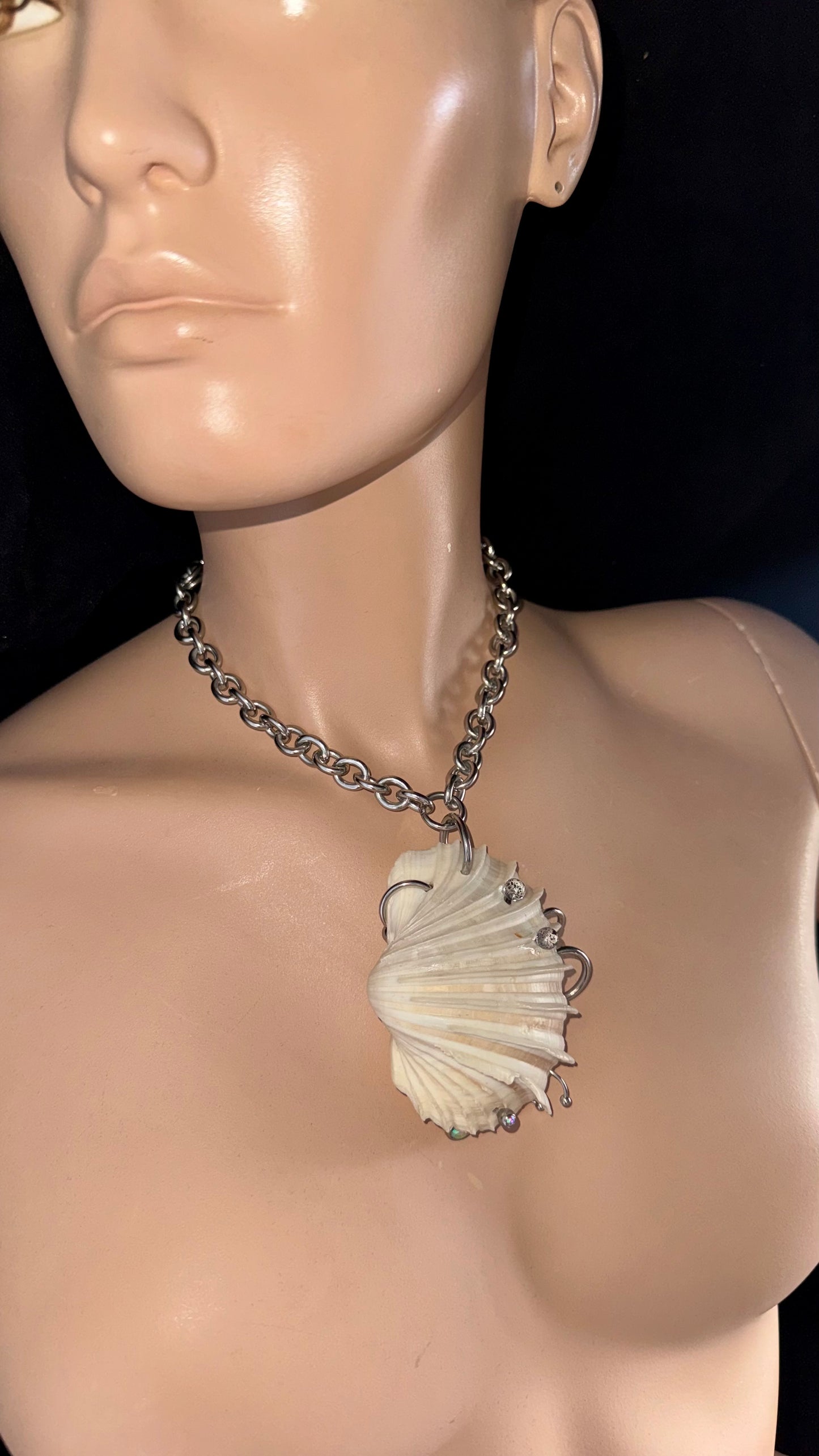 side view of sculptural pierced shell necklace with stainless steel chain