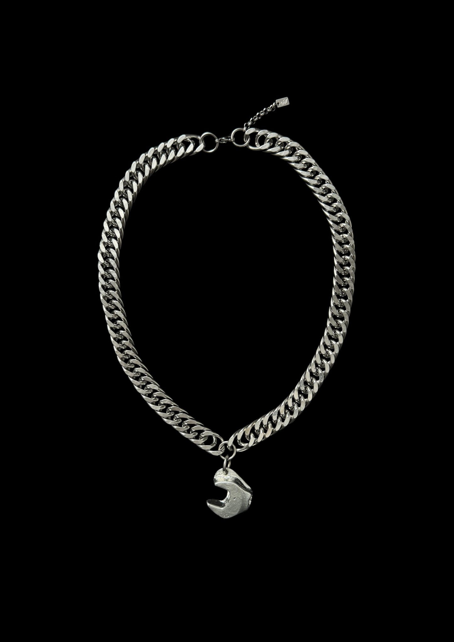 Silver chain bracelet with a small charm on a black background